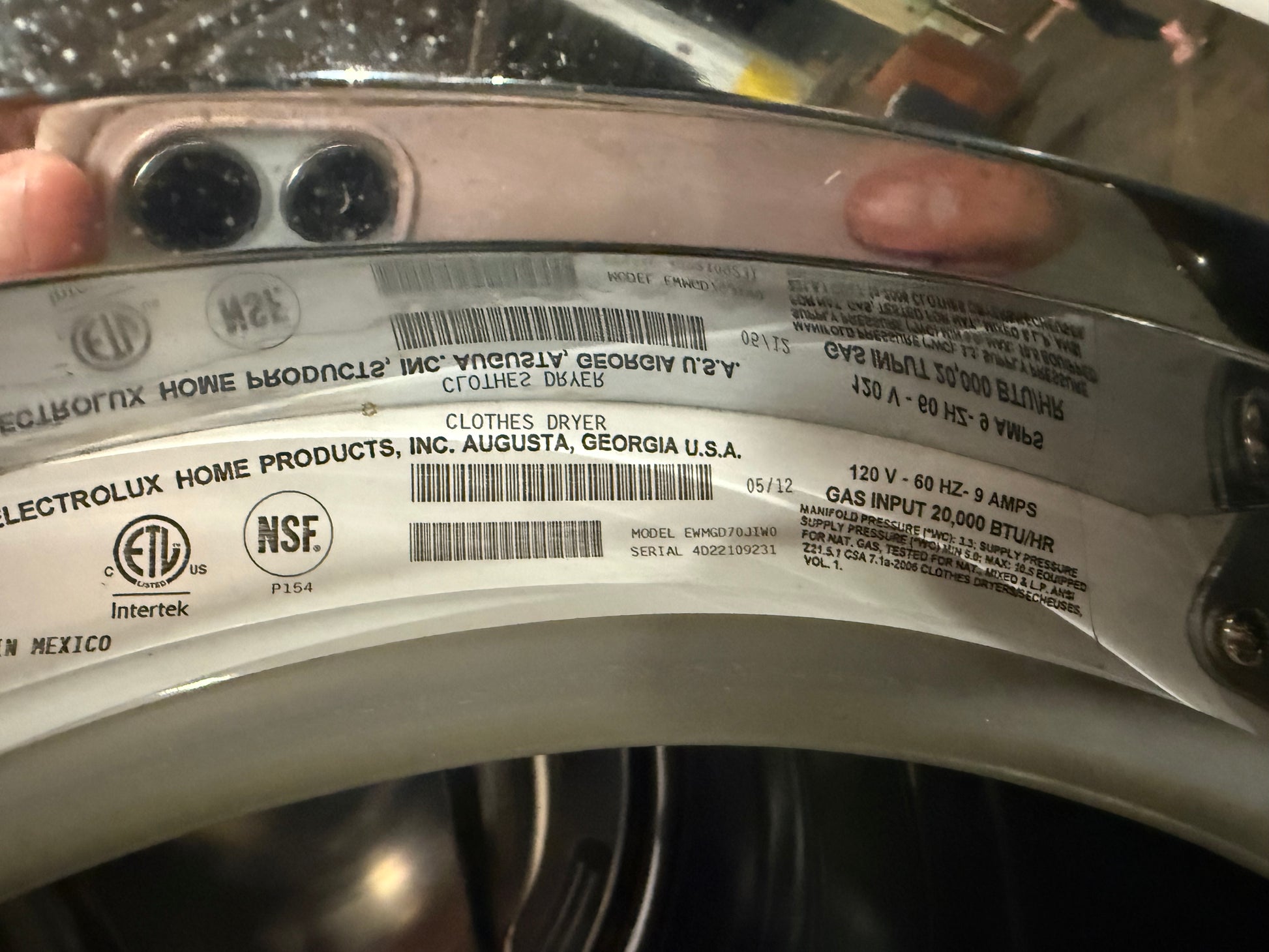 A close-up of a silver Electrolux clothes dryer label sticker showing product specifications, barcodes, and certification logos like ETL and NSF.