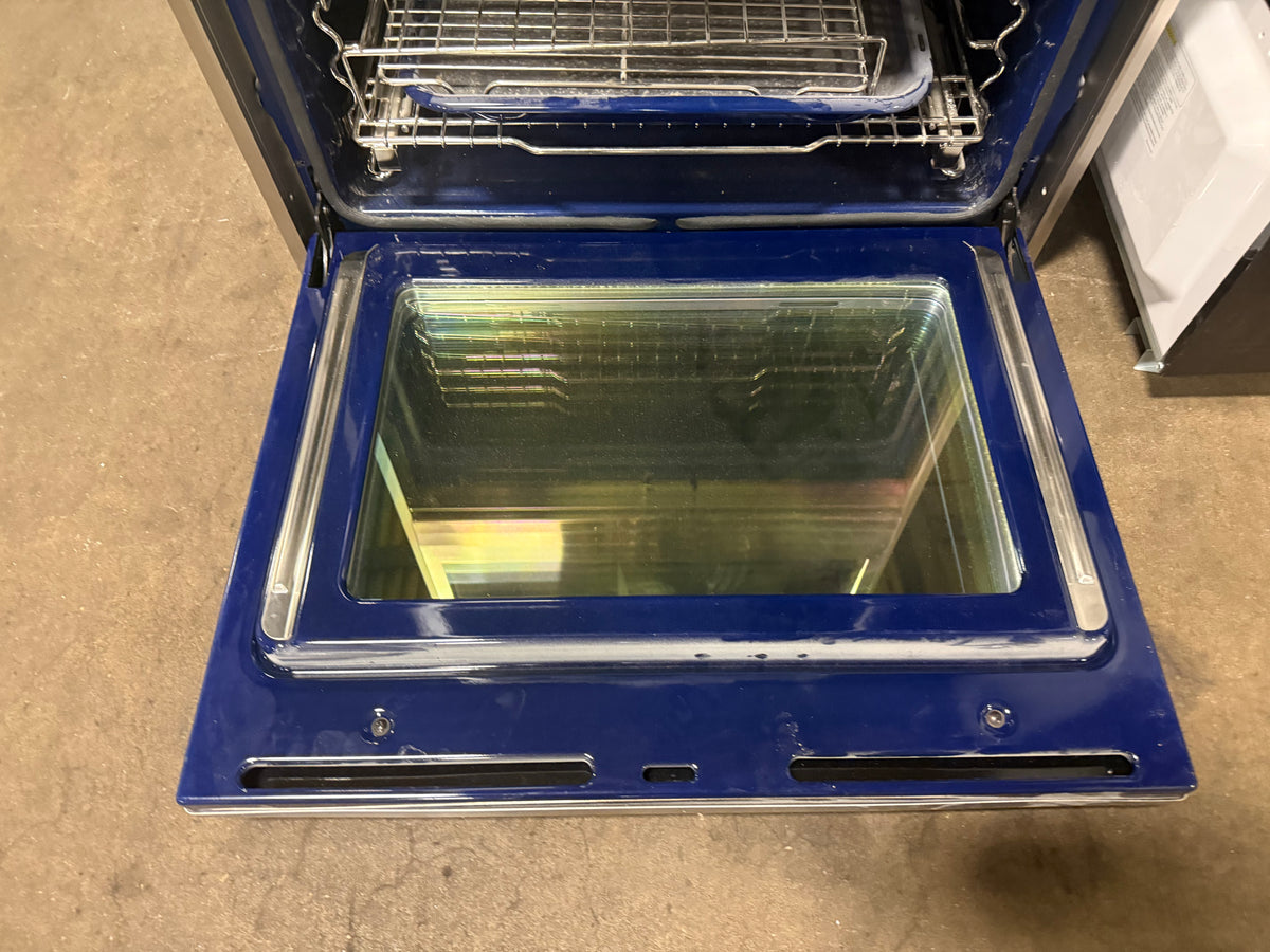 A blue oven with its door open, showing the interior racks and glass door, photographed on a concrete floor.