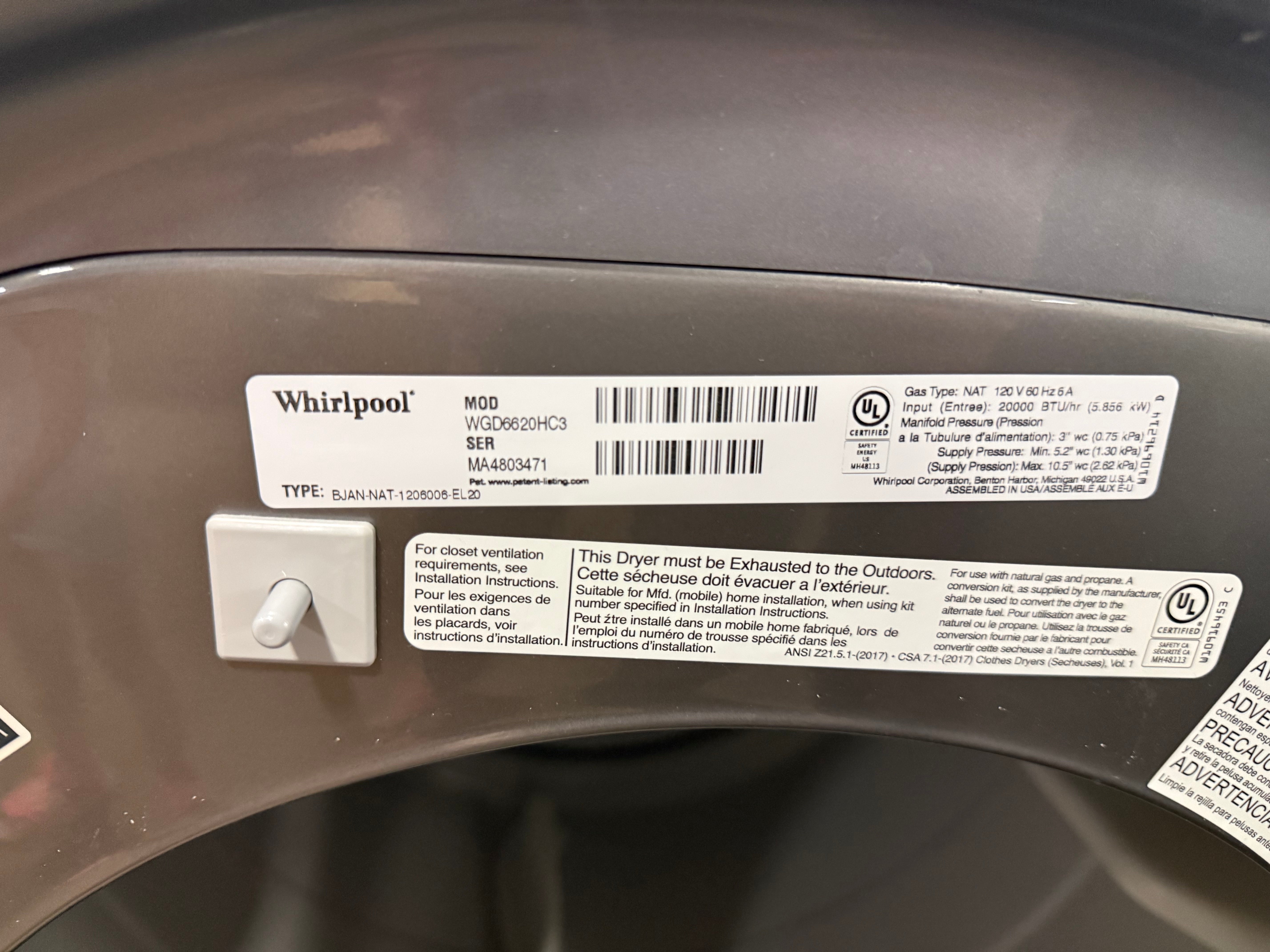 A close-up of a Whirlpool dryer label sticker attached to the dark gray inner door, showing model information, barcodes, and warning text.