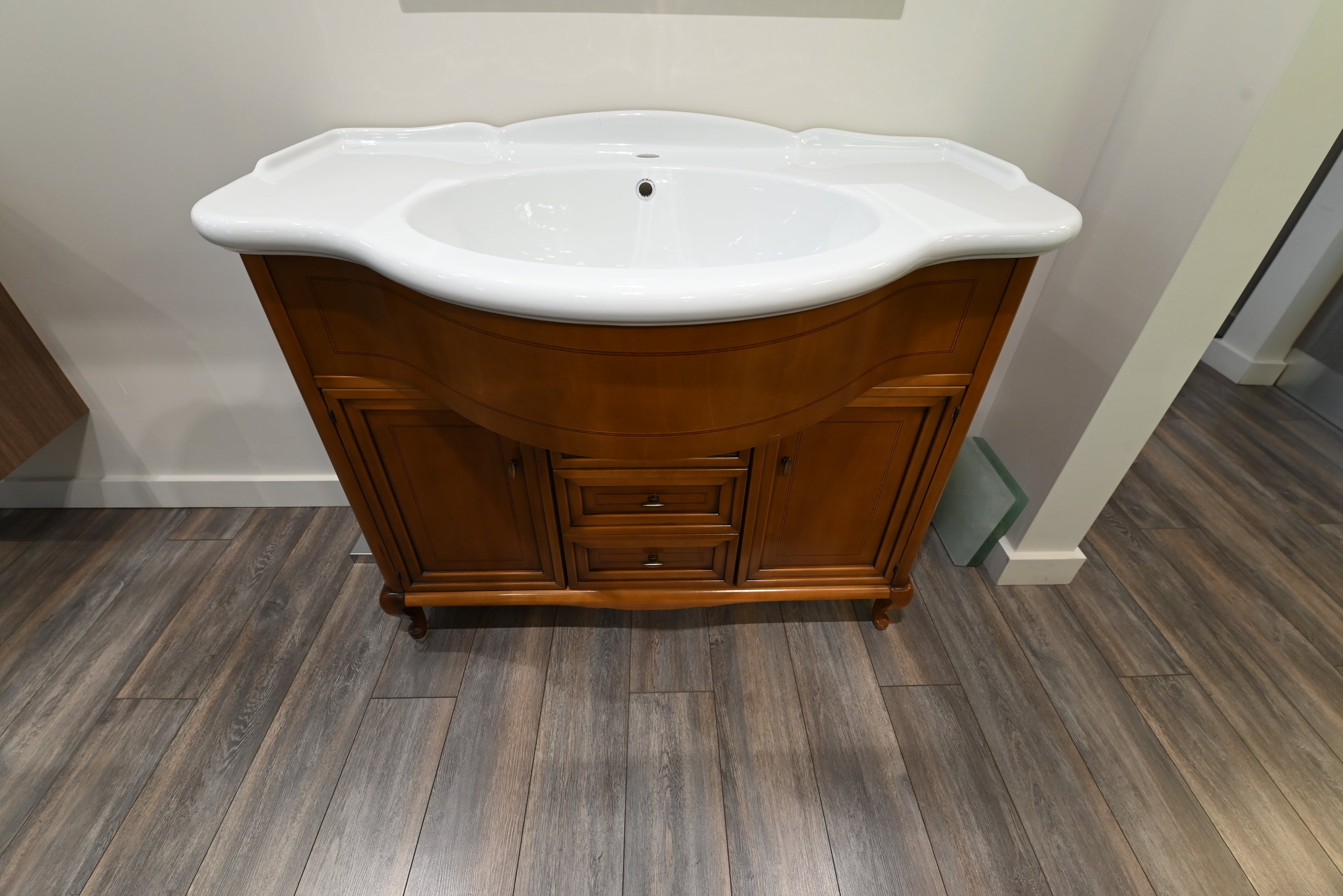 Wooden vanity with white sink on a wooden floor