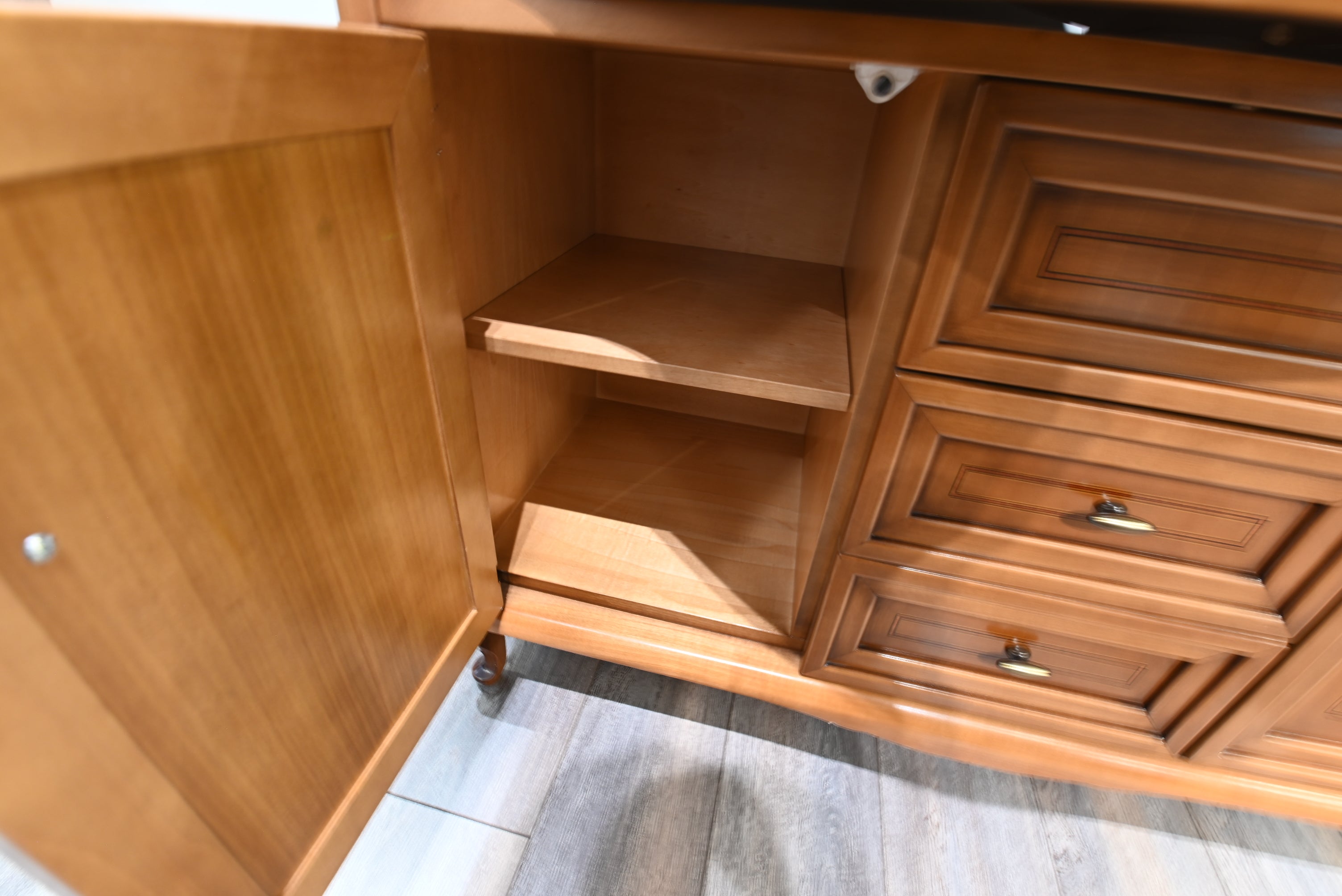 Wooden cabinet with open doors and drawers on a tiled floor