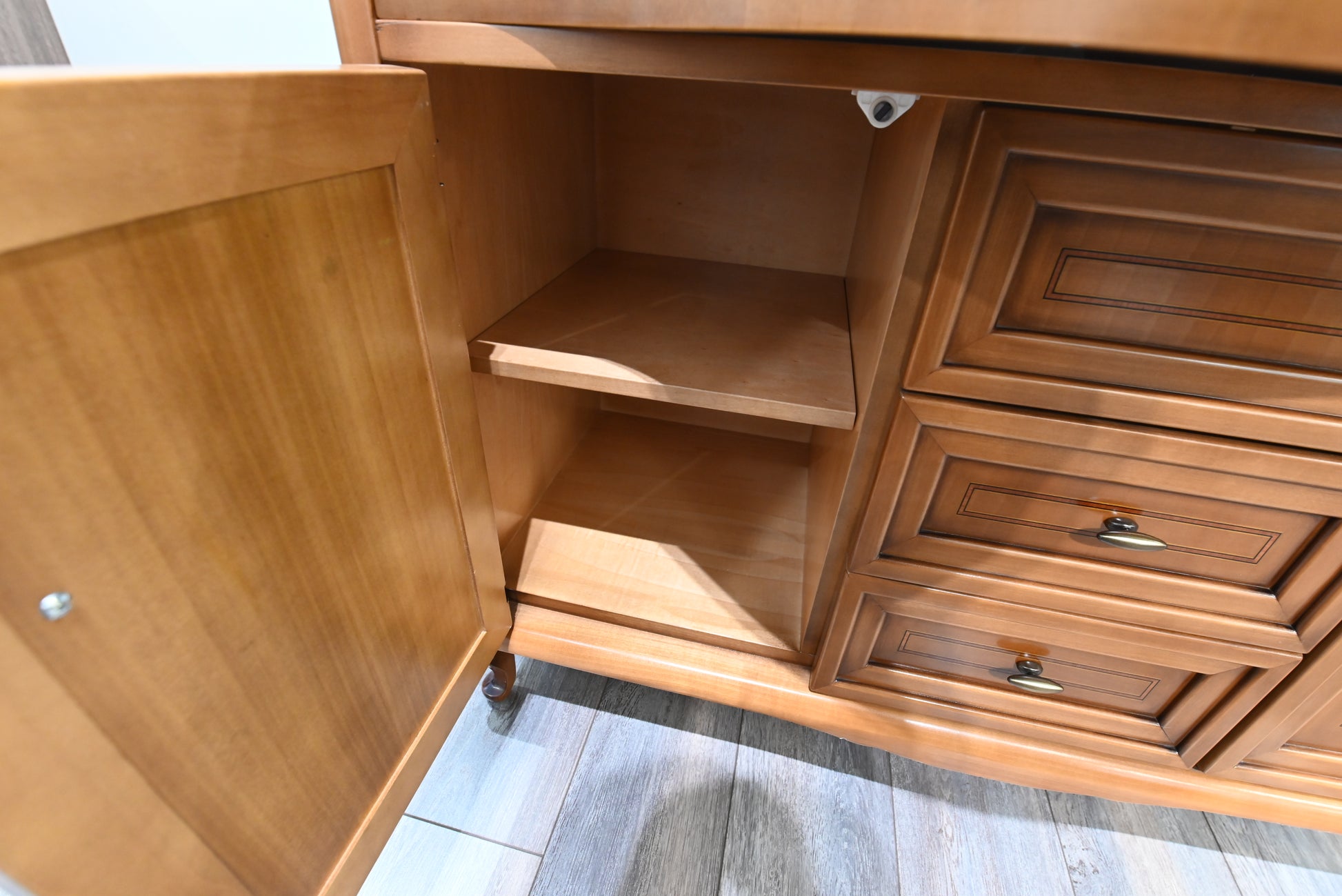 Wooden cabinet with open door and visible shelves on a wooden floor.