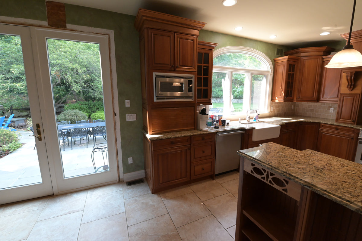 Aurora Circ traditional wooden kitchen with raised panel cabinets built-in microwave granite island sink and bright French doors