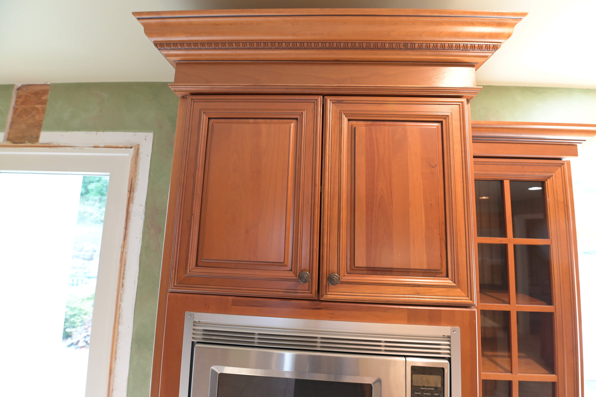 Aurora Circ traditional wood kitchen cabinetry with raised panel doors ornate crown molding glass display cabinet and built in wall oven