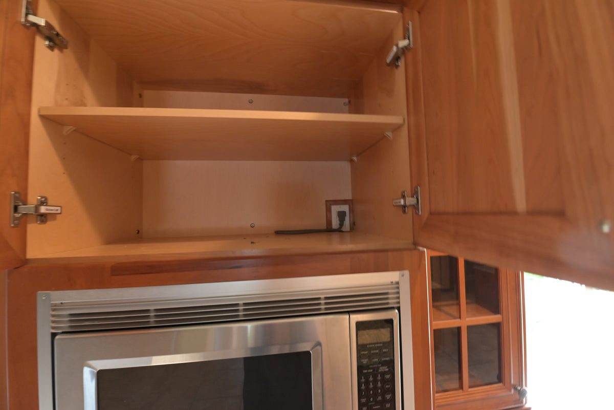 Aurora Circ traditional wood kitchen cabinet with adjustable shelf above a built in stainless steel microwave in a luxury kitchen