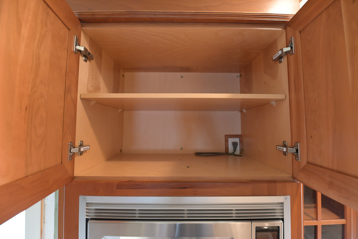 Aurora Circ traditional wood kitchen wall cabinet with open shelving and concealed hinges above a stainless steel appliance