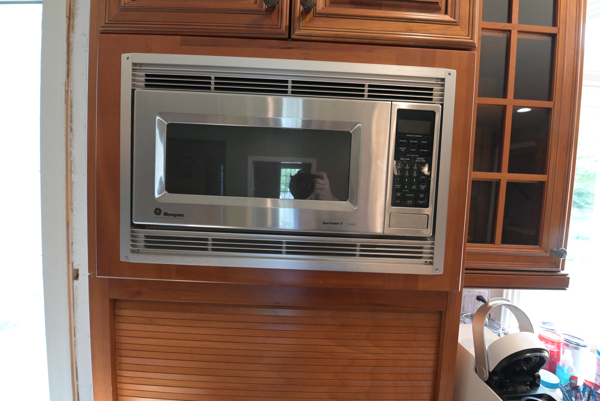 Aurora Circ traditional wood kitchen cabinetry with built-in stainless steel microwave and glass front display cabinet