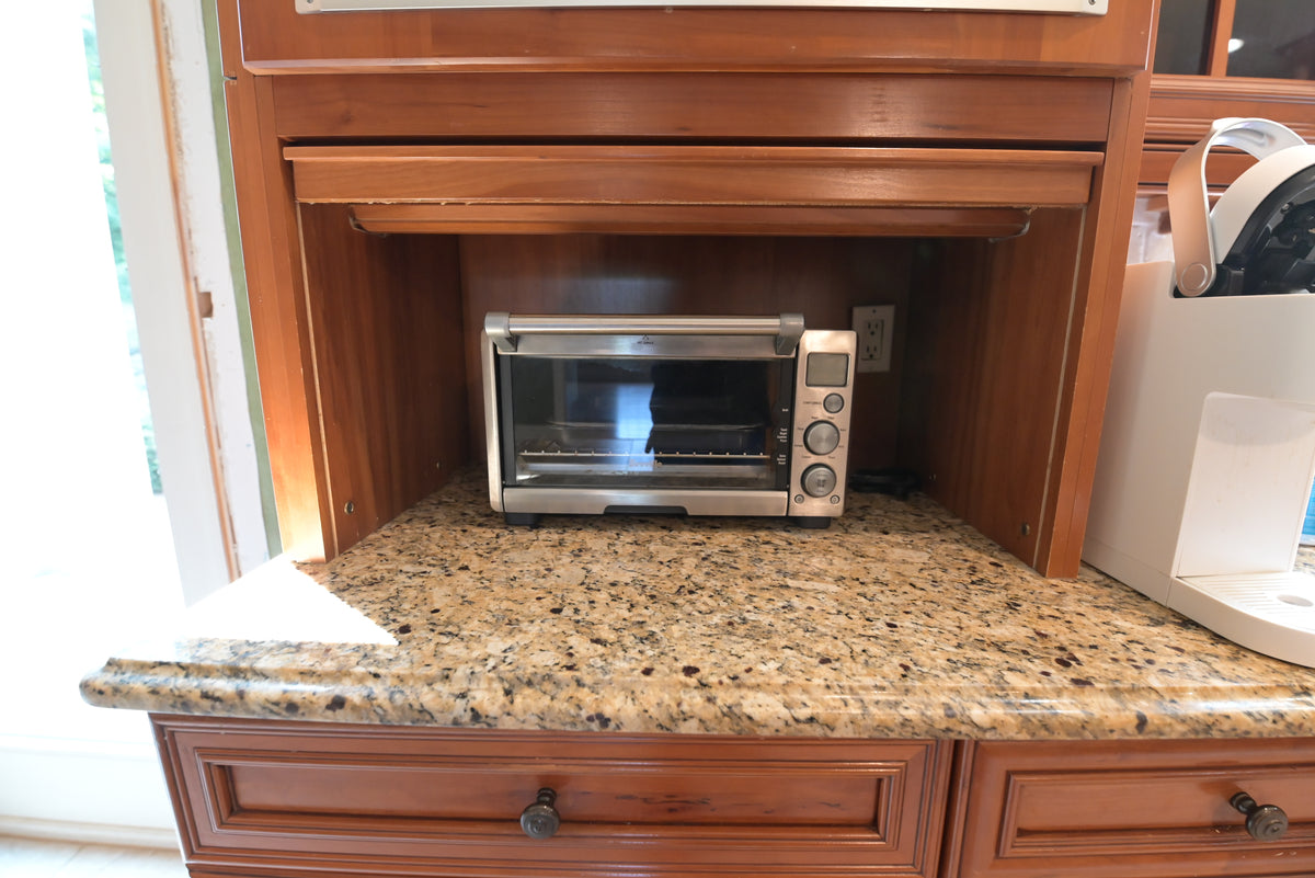 Aurora Circ traditional wooden kitchen cabinetry with granite countertop and stainless steel toaster oven in an appliance niche