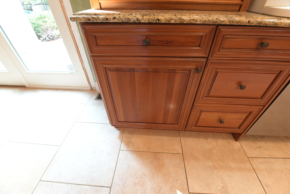 Aurora Circ traditional wood kitchen base cabinets with raised panel doors dark knobs granite countertop and tiled floor