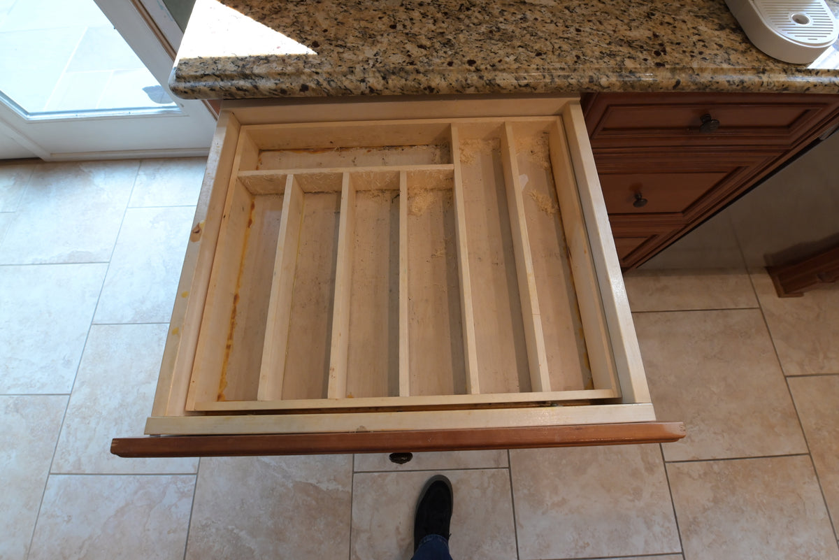 Aurora Circ traditional wood kitchen drawer with built-in utensil dividers beneath a speckled granite countertop