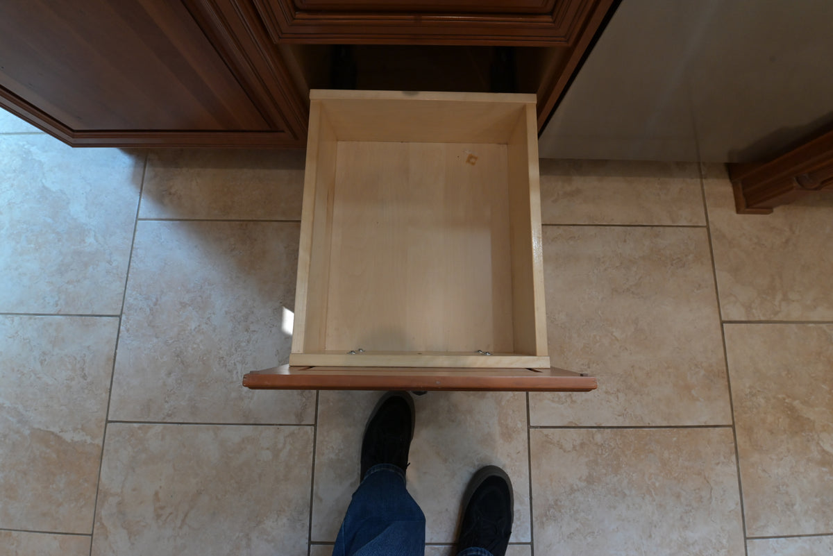 Aurora Circ traditional wooden kitchen cabinet with an open light wood drawer above tiled flooring