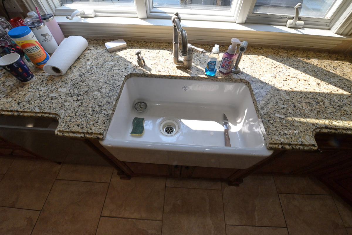 Aurora Circ traditional wooden kitchen with speckled granite countertop white farmhouse sink and brushed metal faucet