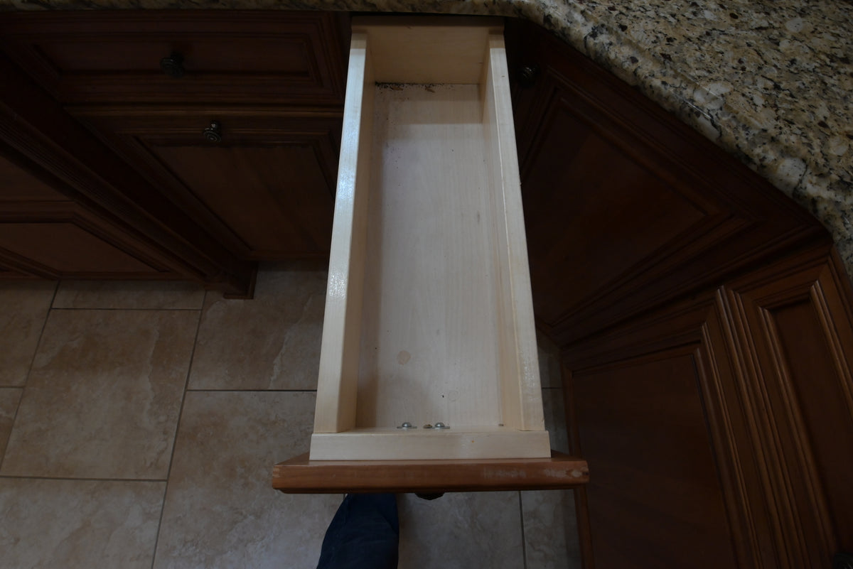 Aurora Circ traditional wooden kitchen cabinet with an open narrow drawer beneath a speckled granite countertop
