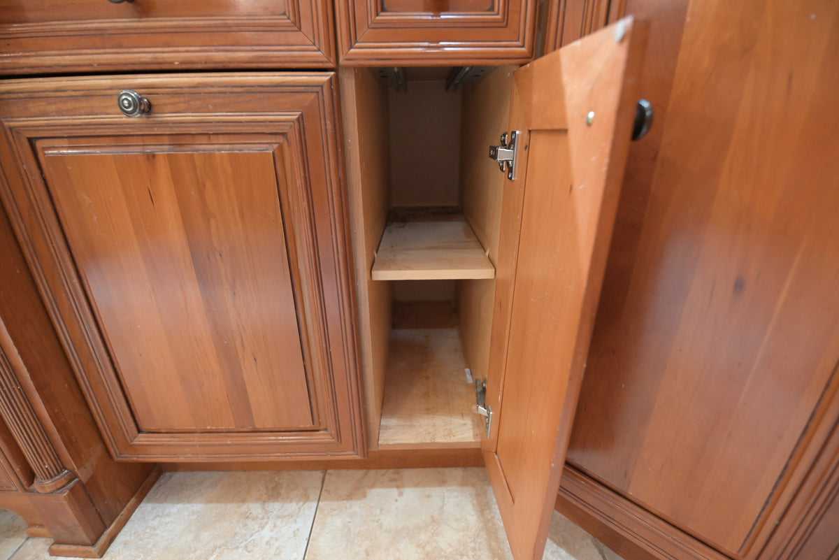 Aurora Circ traditional wooden kitchen cabinet with open door revealing interior shelving and warm raised panel detailing