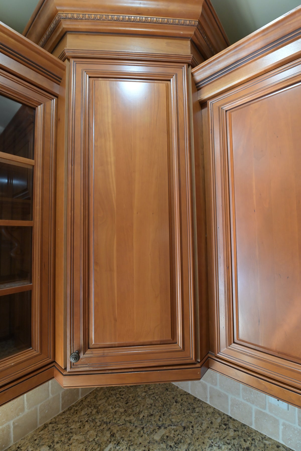 Aurora Circ traditional wood kitchen corner cabinet with raised panel doors above granite countertop and tiled backsplash