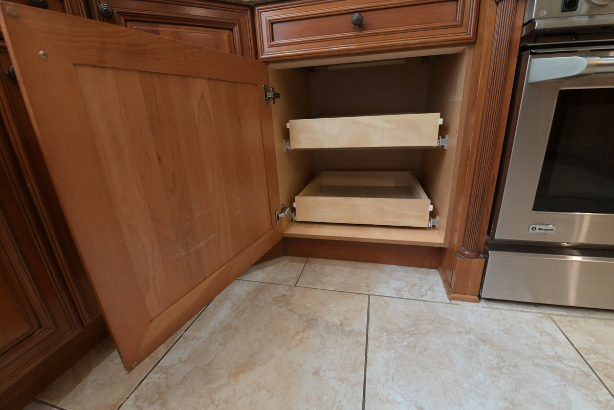 Aurora Circ traditional wood kitchen cabinet open to reveal two pullout storage shelves beside a stainless steel wall oven