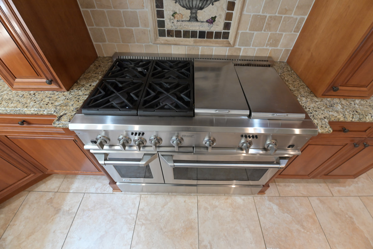 Aurora Circ traditional wooden kitchen with stainless steel range and gas cooktop set between warm wood cabinets