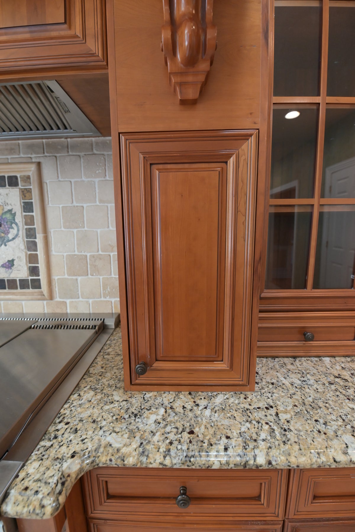 Aurora Circ traditional wooden kitchen cabinetry with a raised panel door glass front storage and speckled granite countertop