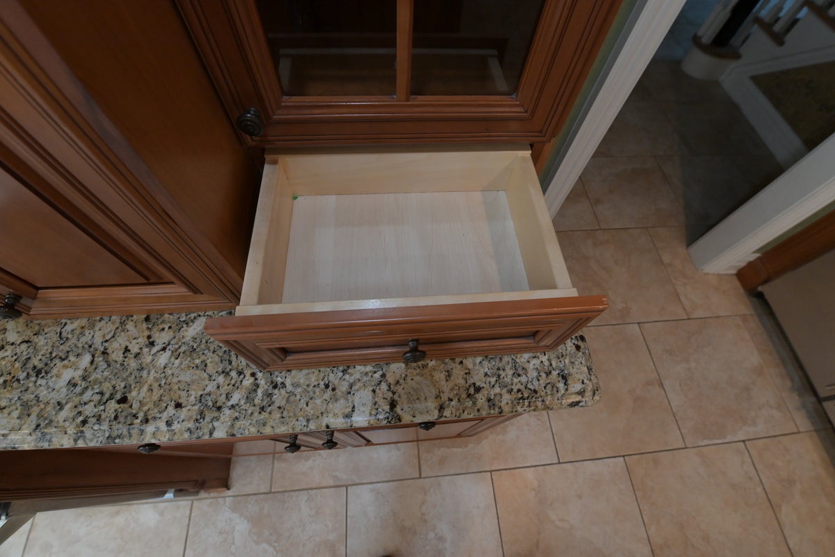 Aurora Circ traditional wooden kitchen cabinet with an open drawer beneath a speckled granite countertop