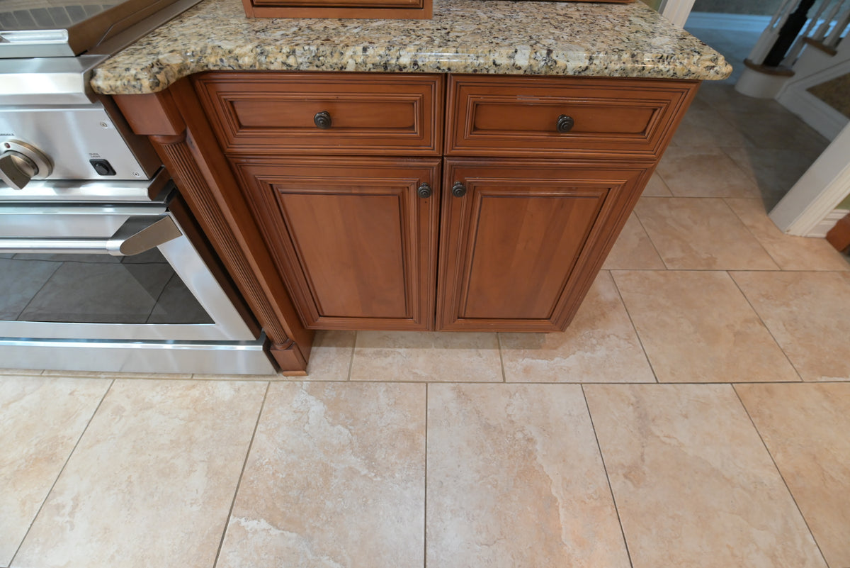 Aurora Circ traditional wooden kitchen island with raised panel doors dark hardware and speckled granite countertop beside a stainless steel range