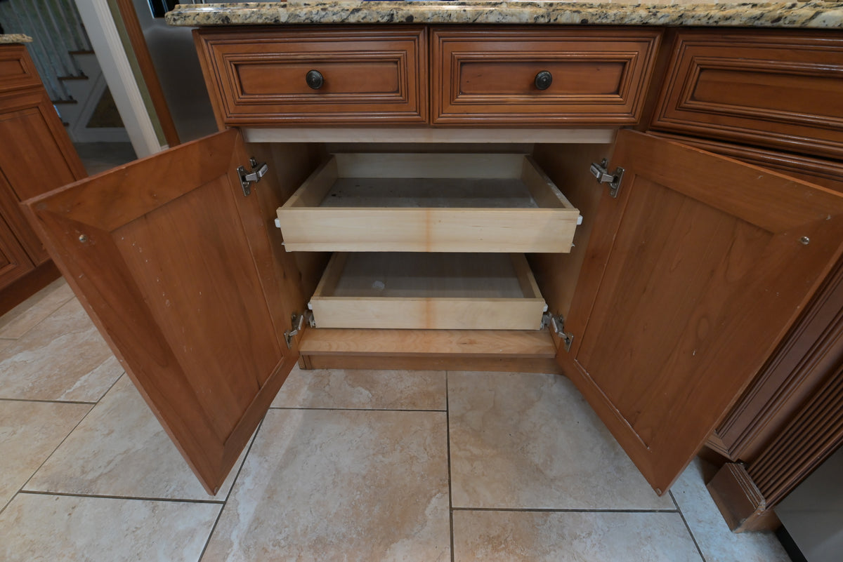 Aurora Circ traditional wooden kitchen cabinet with open pullout drawers beneath a granite countertop and paneled doors
