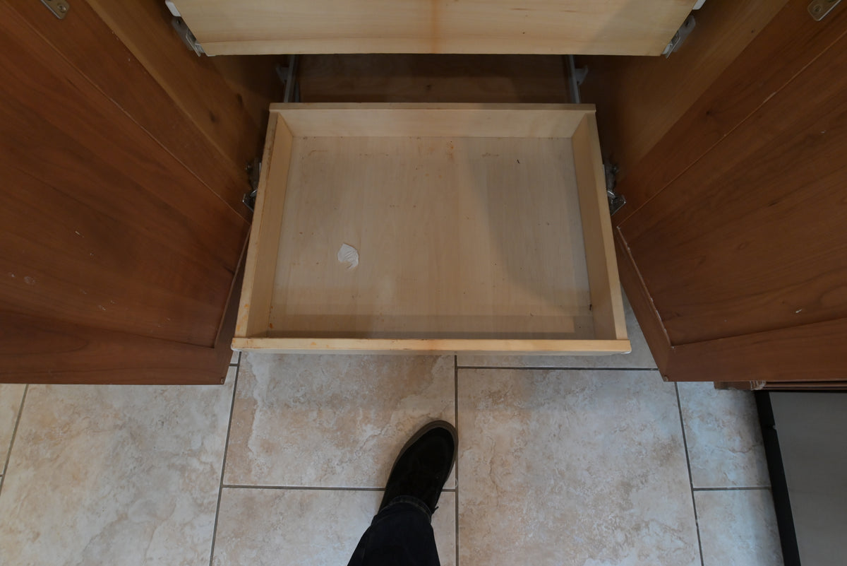Aurora Circ traditional wooden kitchen cabinet drawer open to reveal its natural wood interior above tiled flooring