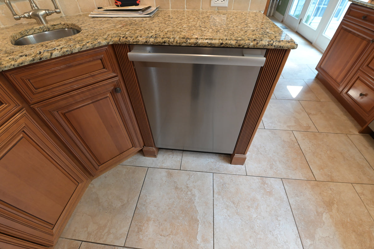 Aurora Circ traditional wood kitchen cabinetry with raised panel doors and stainless steel dishwasher beneath a granite countertop