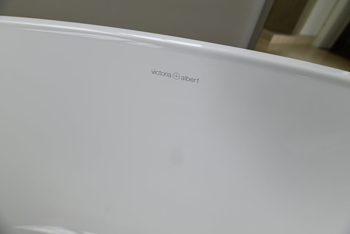 Close-up of a white freestanding bathtub corner with the Victoria Albert brand name printed in small gray text on the inner rim.