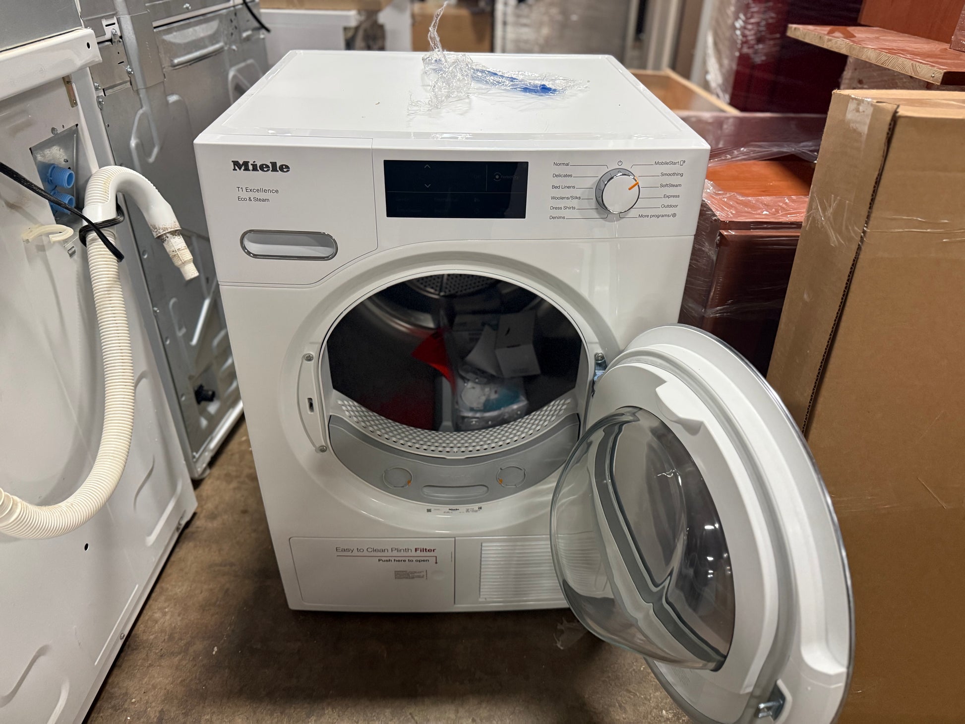 White Miele dryer with open door in a storage or warehouse setting