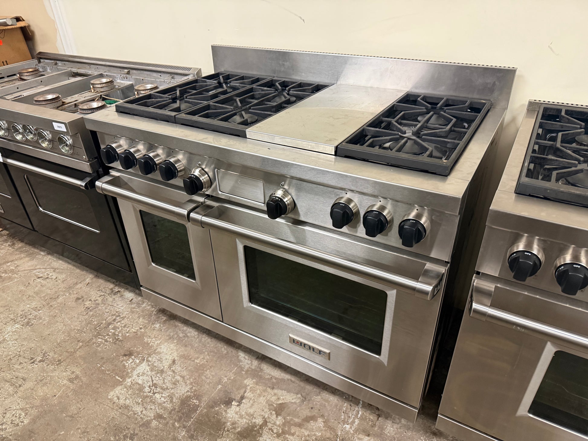 Pre owned Wolf 48 inch dual fuel range open doors showing dual electric oven cavities with cobalt blue porcelain interiors