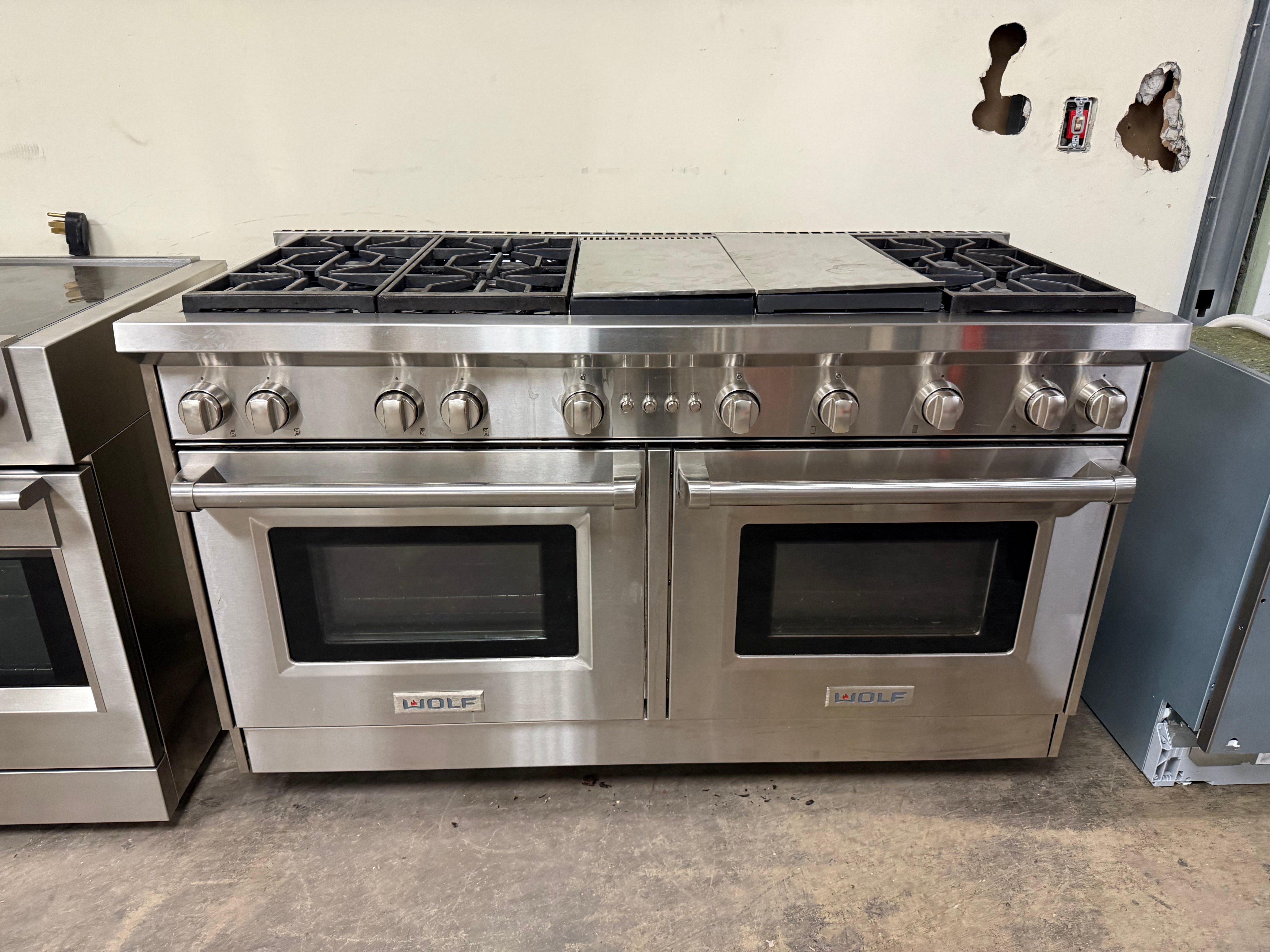 A luxury kitchen featuring a massive 60-inch Wolf gas range with signature red control knobs and double ovens.