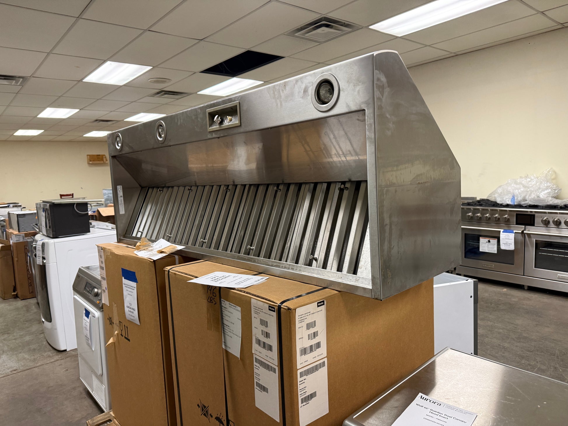 Luxury professional 66 inch range hood underside showing extended stainless steel baffle filters and halogen task lighting