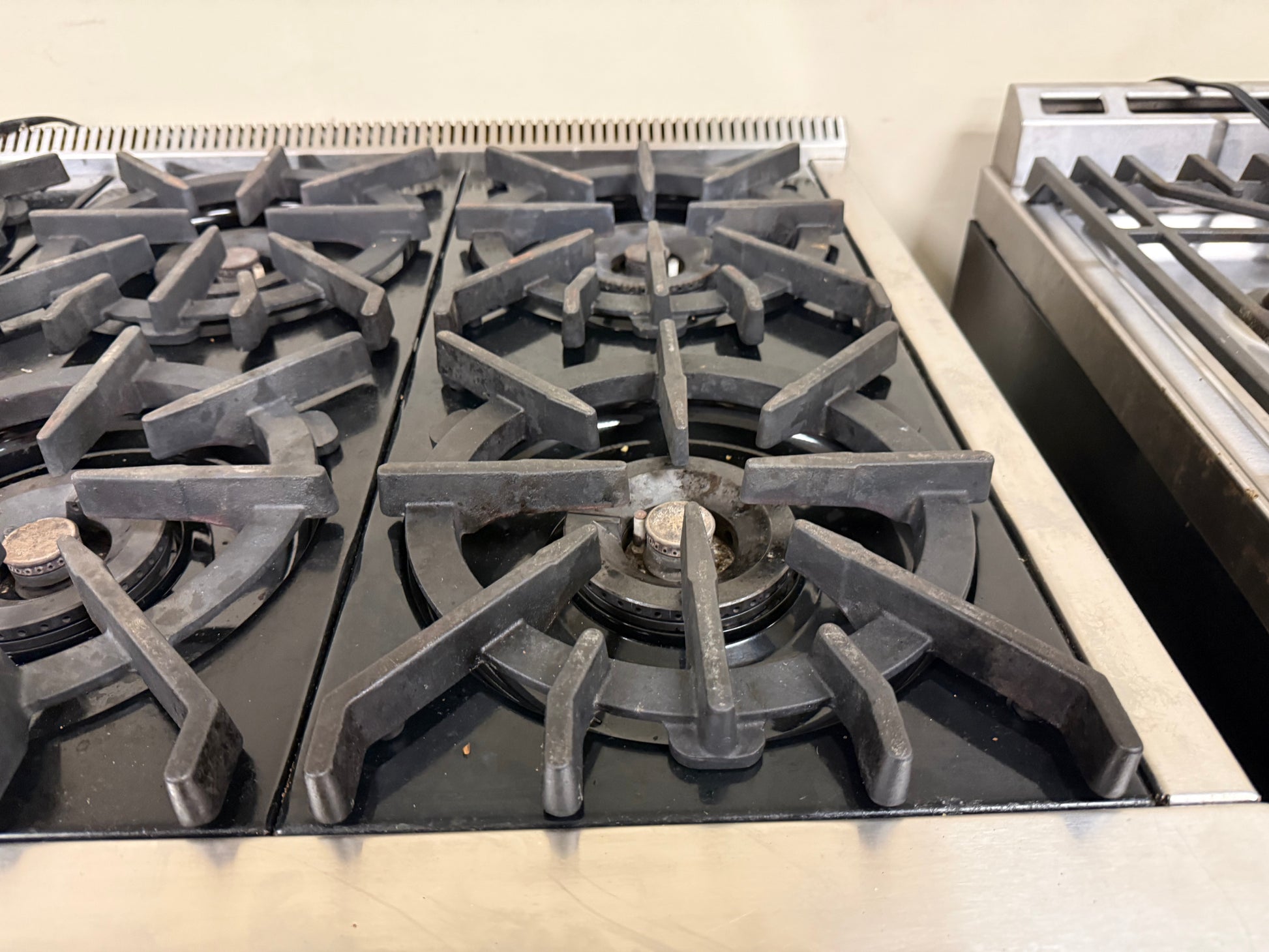 Stainless steel gas stove with visible burners on a beige countertop.
