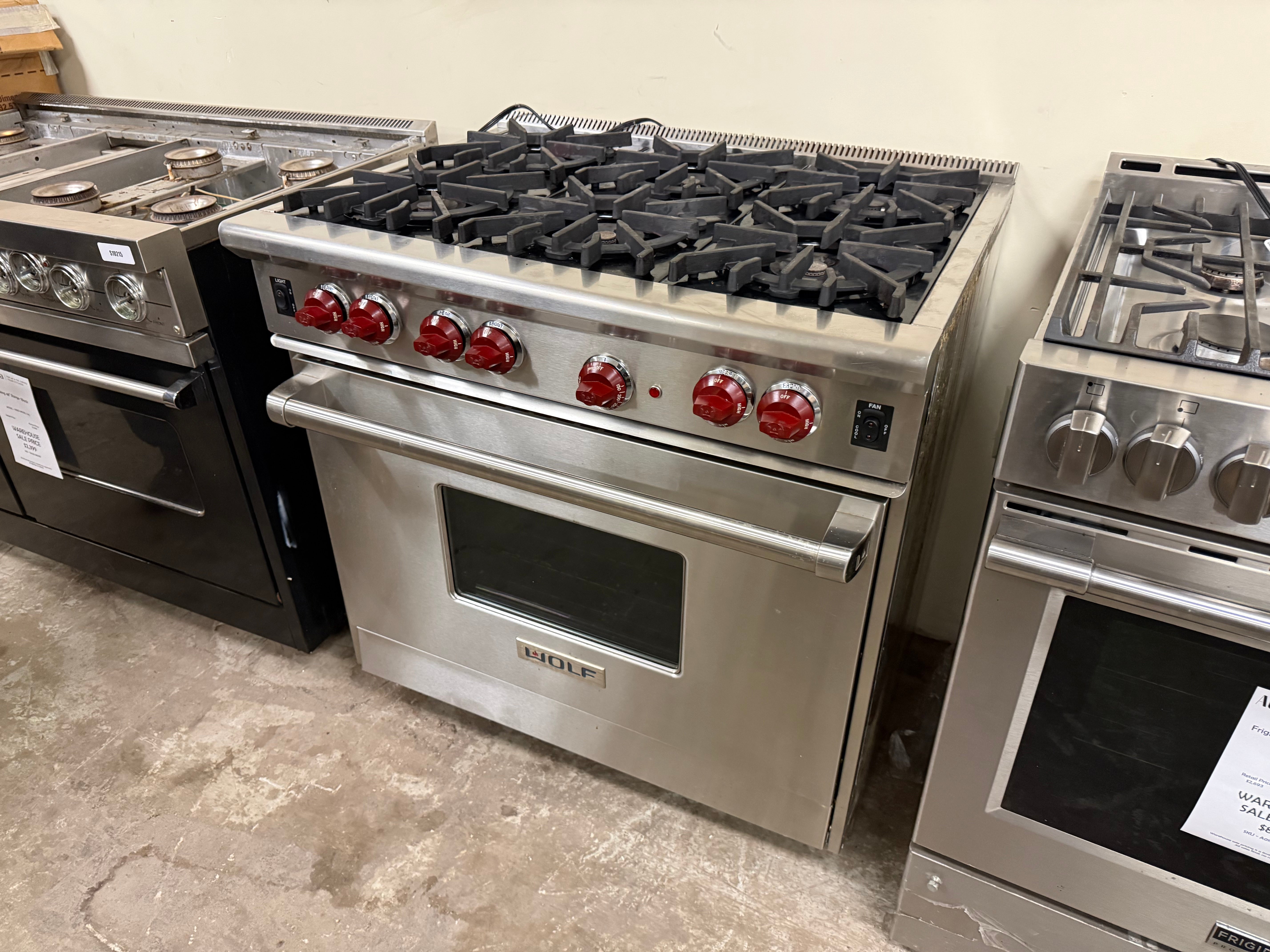 Stainless steel stoves with gas burners on a concrete floor.