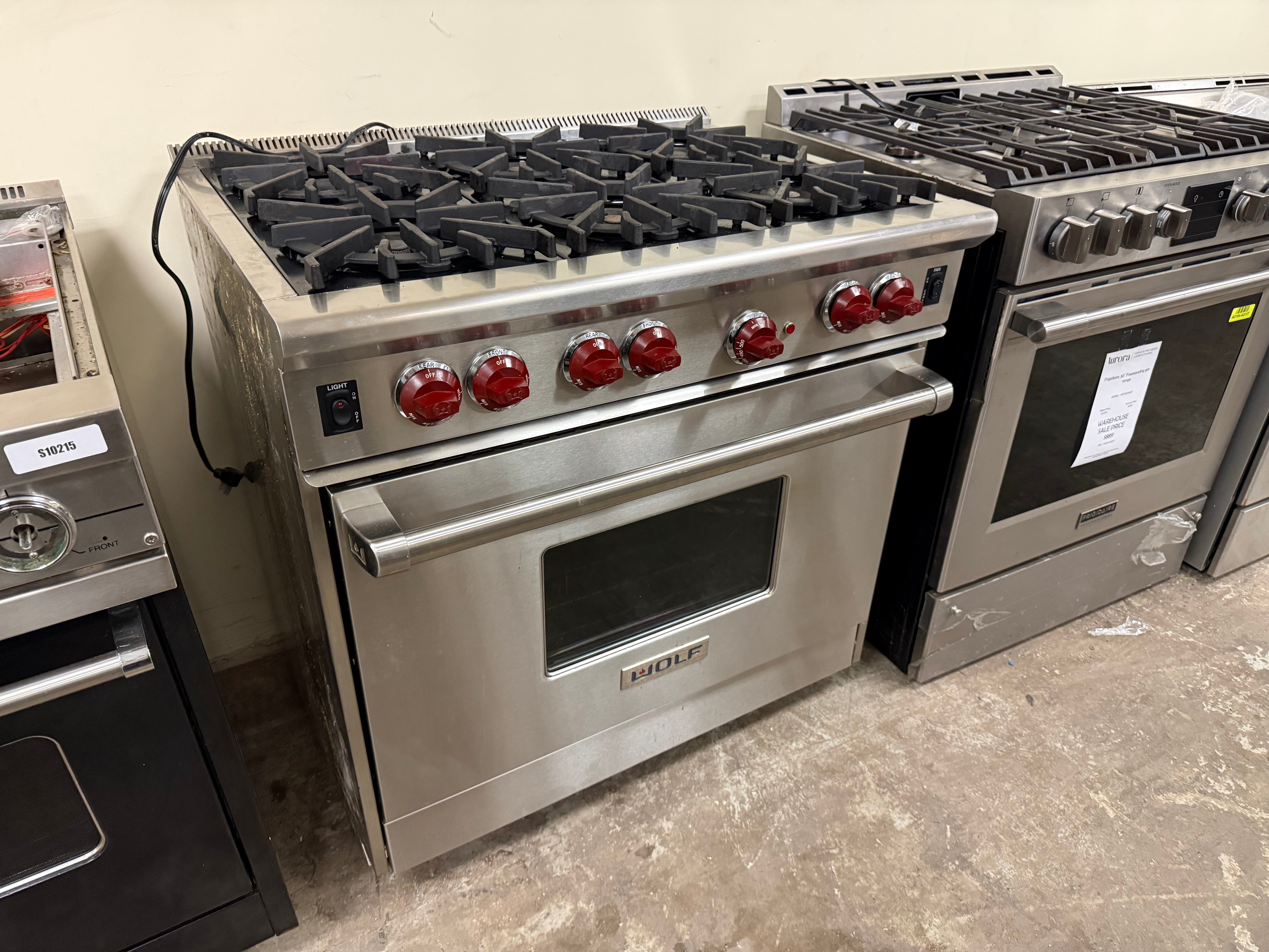 Stainless steel kitchen stoves with gas burners and ovens on a concrete floor.