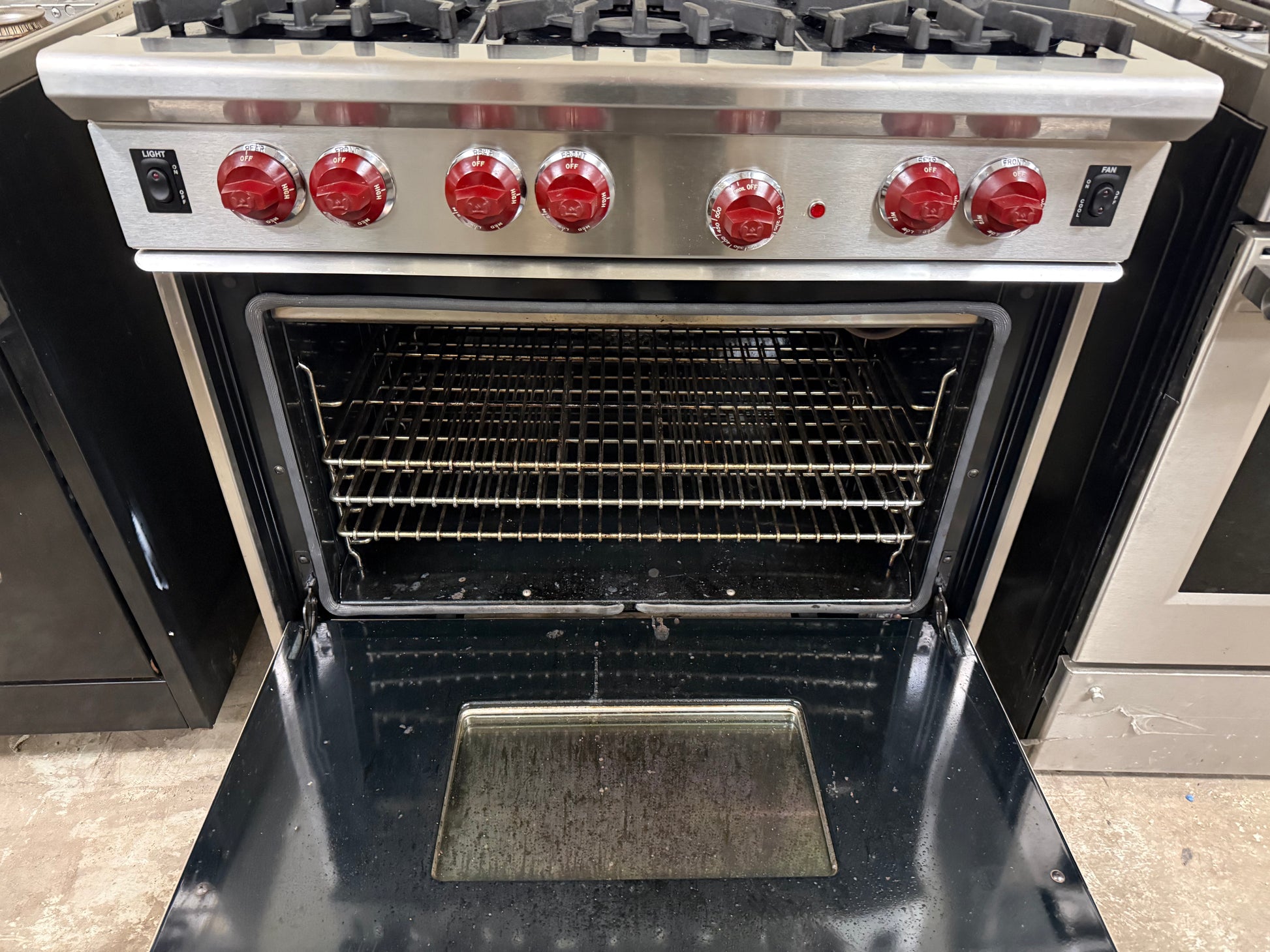 Stainless steel oven with open door showing interior racks on a kitchen counter.