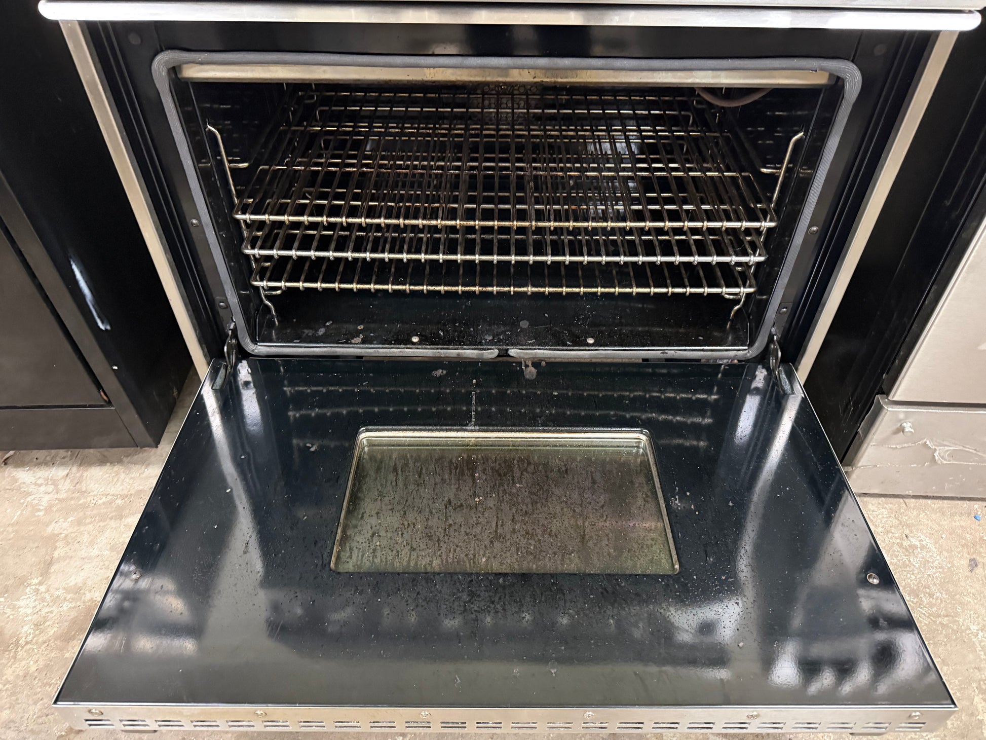 Open black oven with a rack inside, showing signs of use.