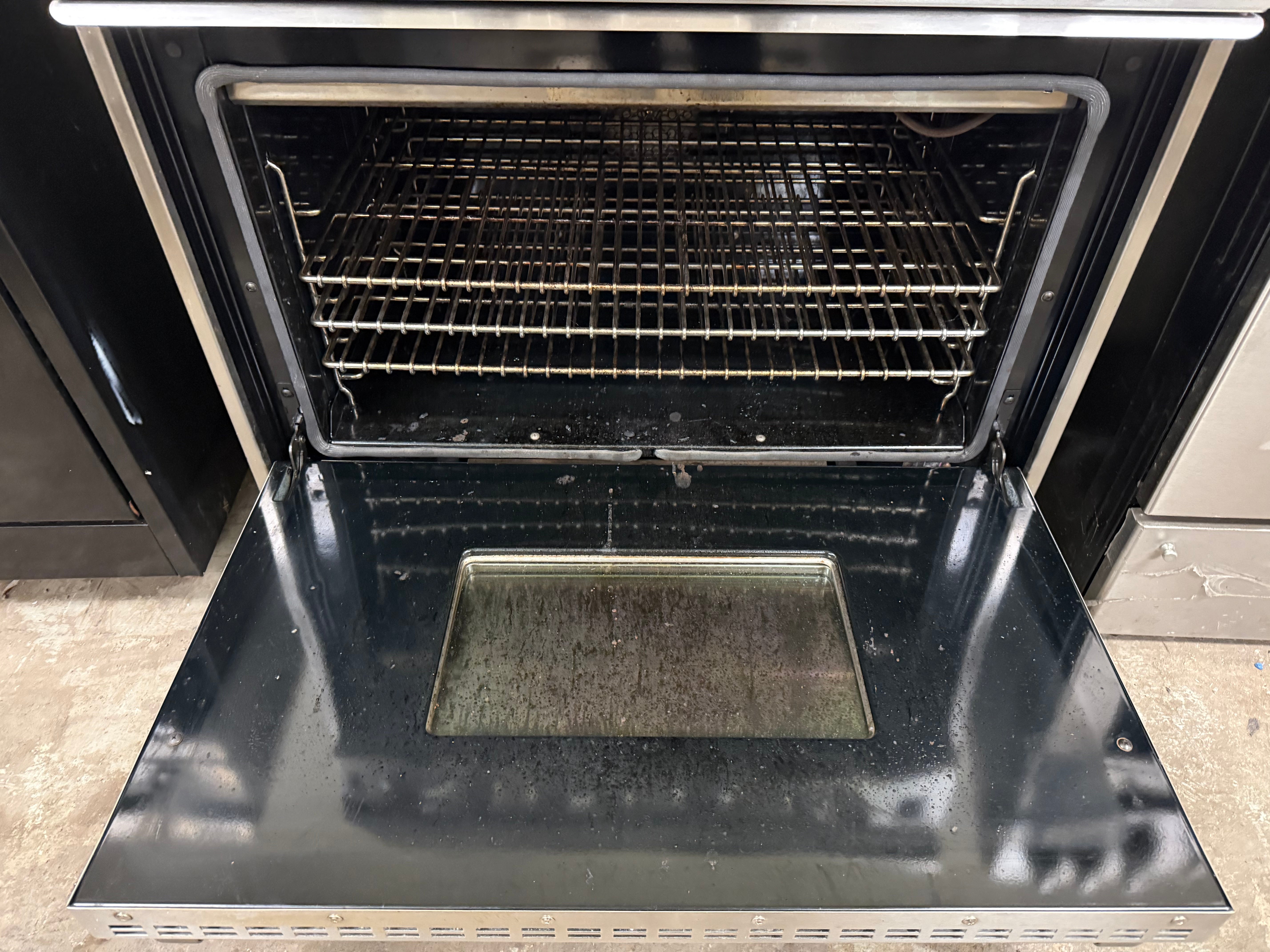Open black oven with a rack inside, showing signs of use.