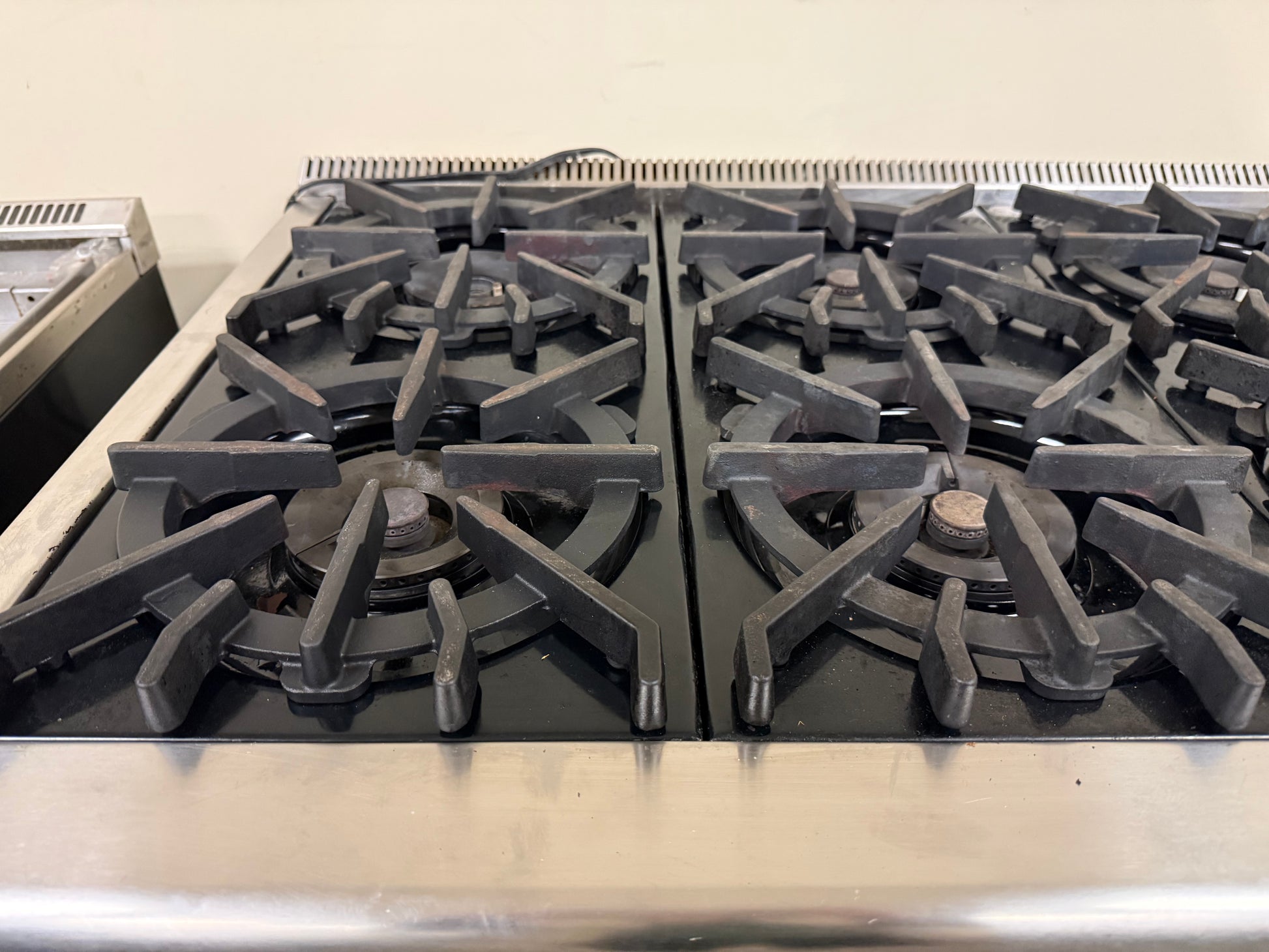 Stainless steel gas stove with four burners on a beige background