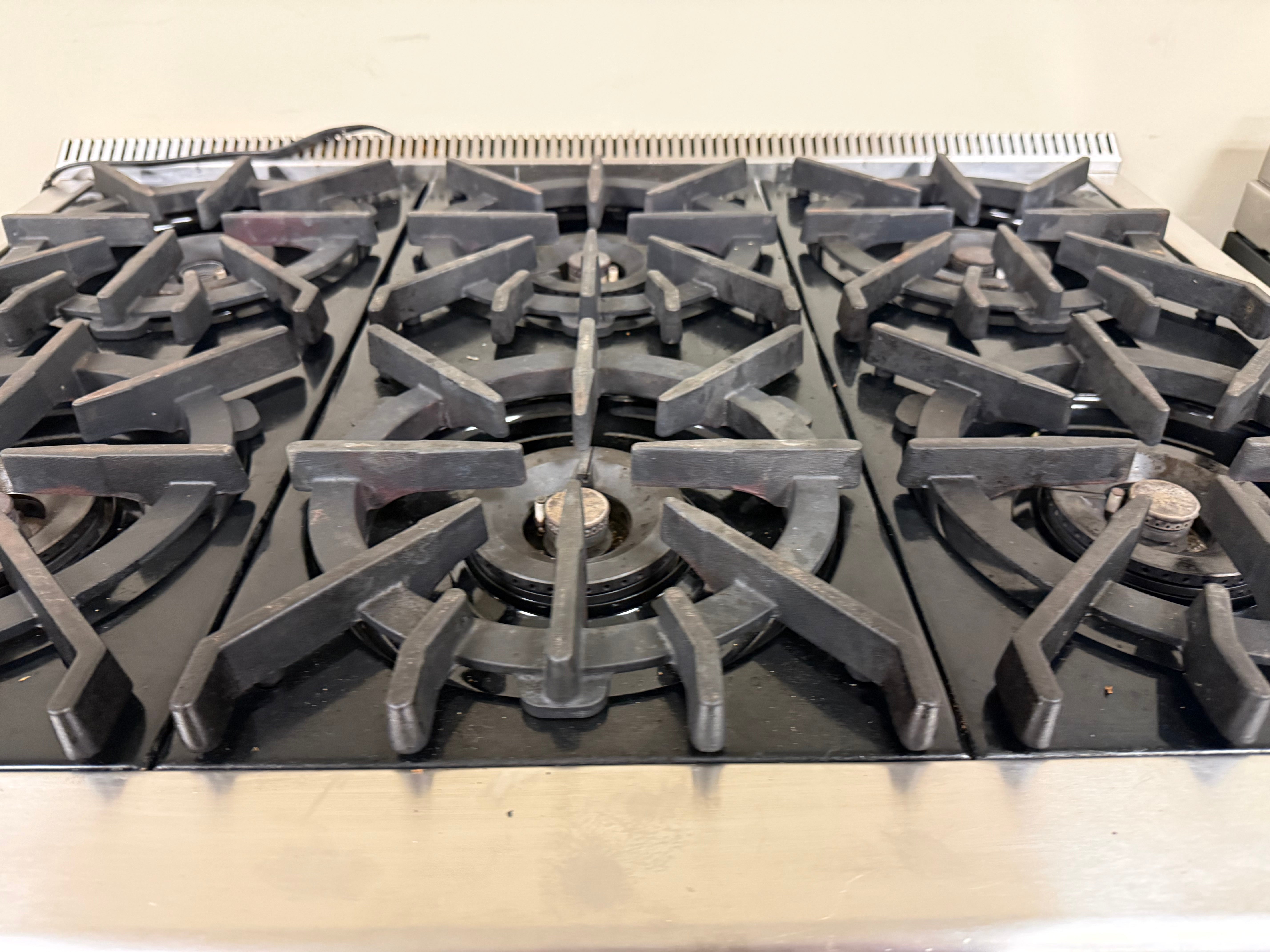 Stainless steel gas stove with black grates on a white background