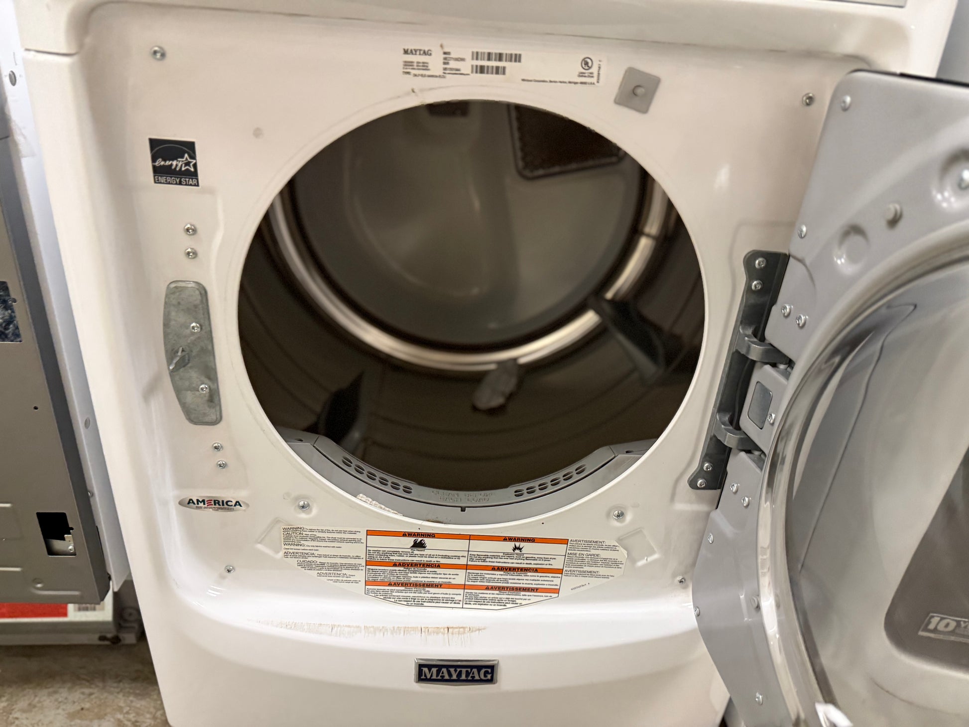 White dryer with open door showing interior in a laundry room setting.