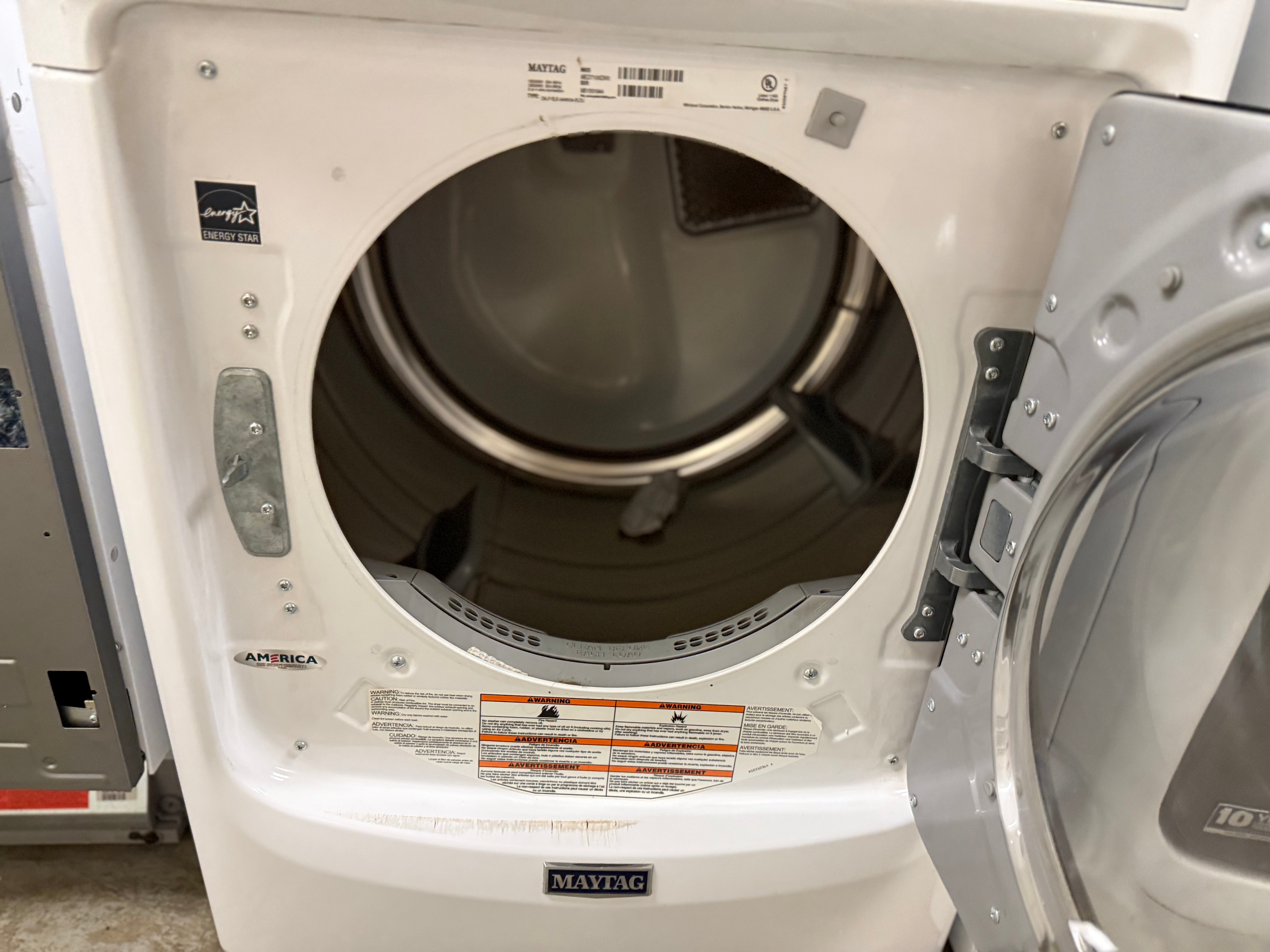 White dryer with open door showing interior in a laundry room setting.