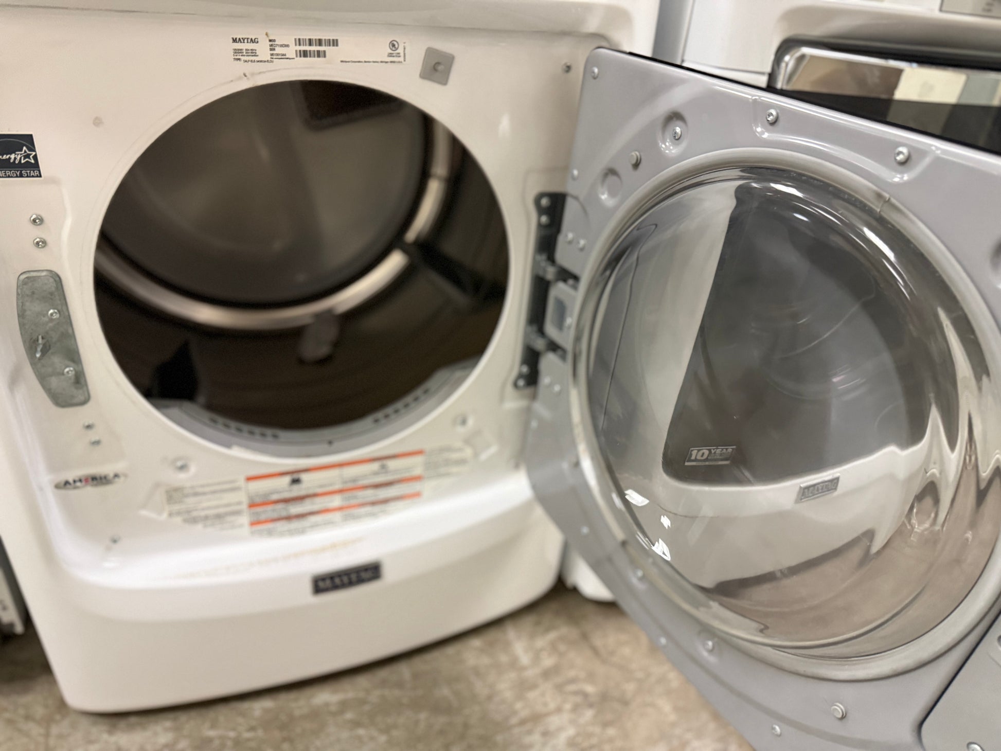 White washer and dryer with open door in a laundry room.