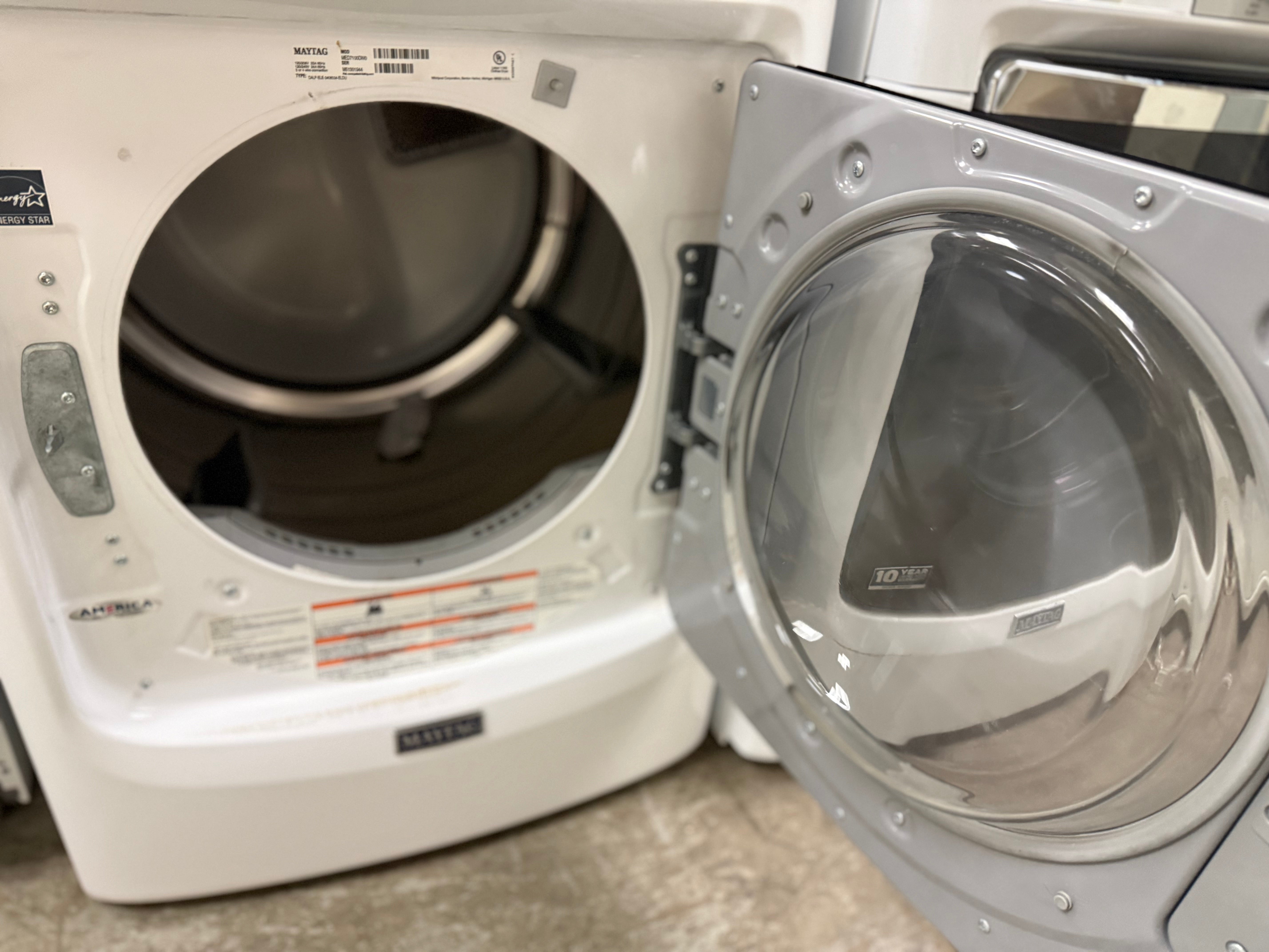 White washer and dryer with open door in a laundry room.