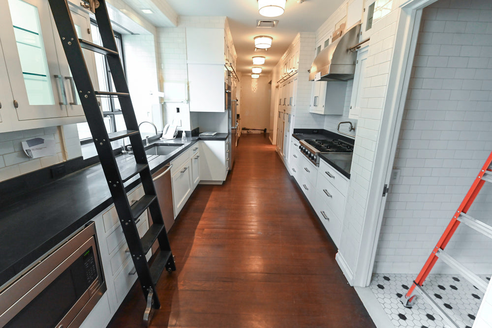 Modern kitchen with white cabinets, black countertops, and tiled walls.