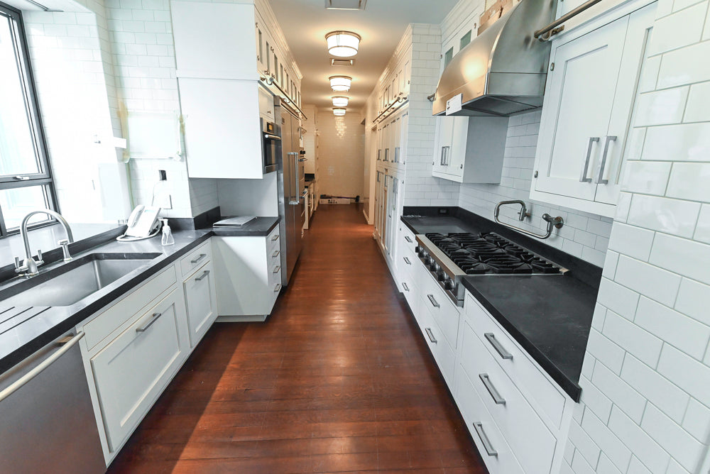 Modern kitchen with white cabinets, black countertops, and tiled walls.