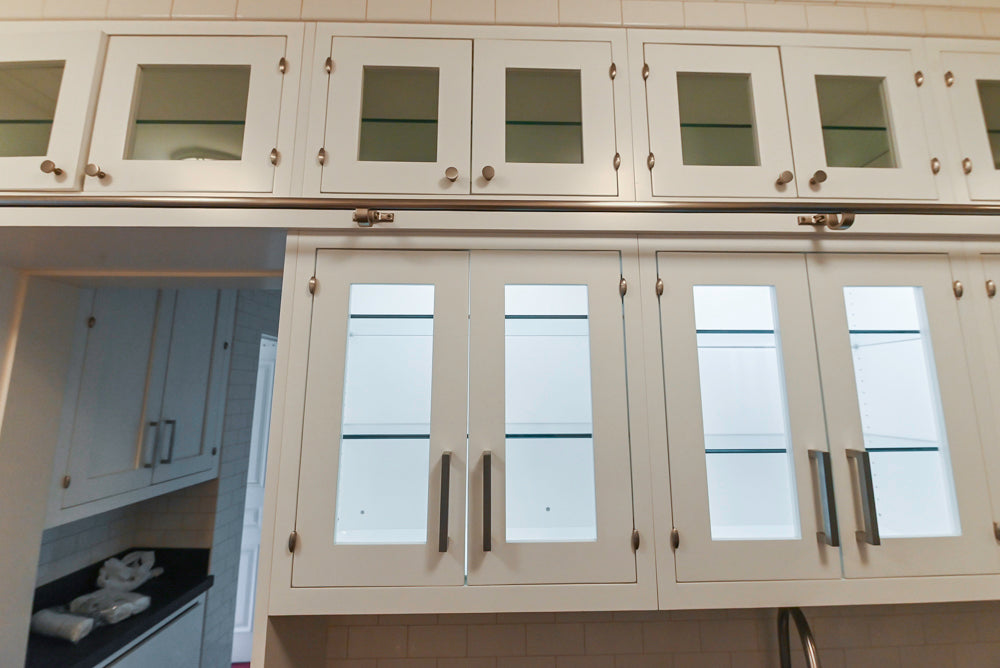 Beige kitchen cabinets with glass panels and metallic handles.