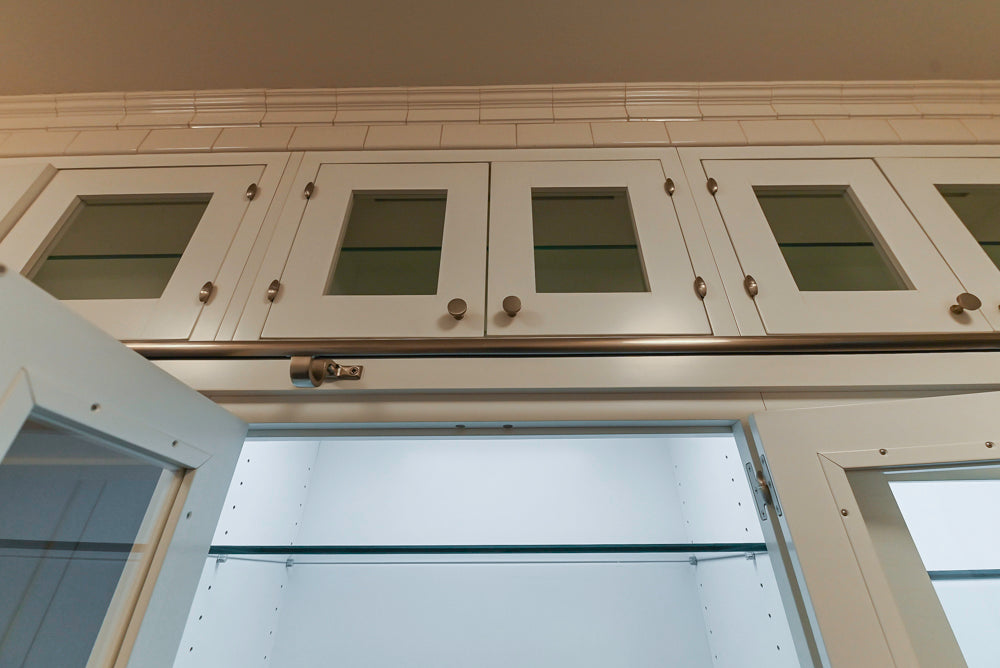 White kitchen cabinets with glass panels above a white door.