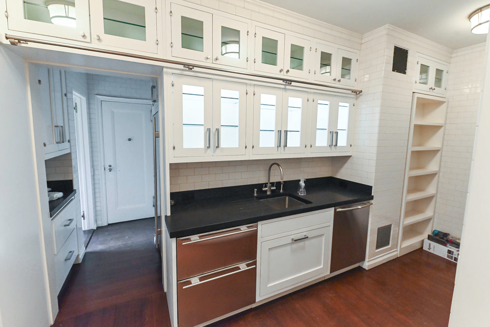 Modern kitchen with white cabinets, black countertops, and stainless steel appliances.
