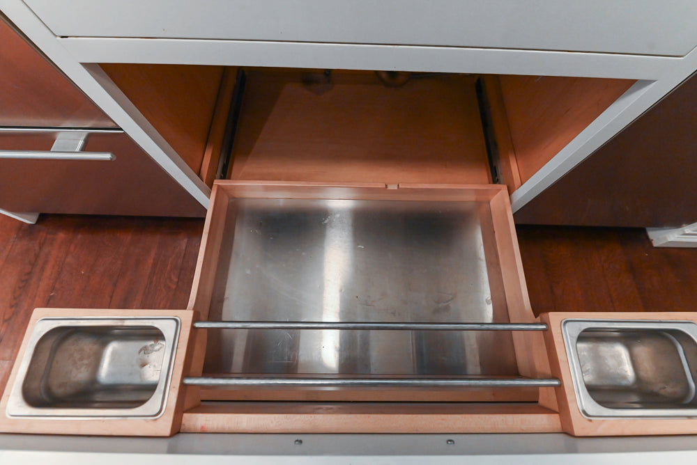 Open kitchen drawer with metallic interior and wooden sides.